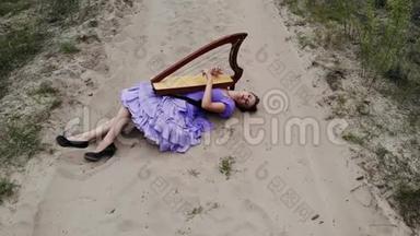 在沙漠里躺在沙滩上弹奏<strong>竖琴</strong>的女<strong>竖琴</strong>师的无人机射击。